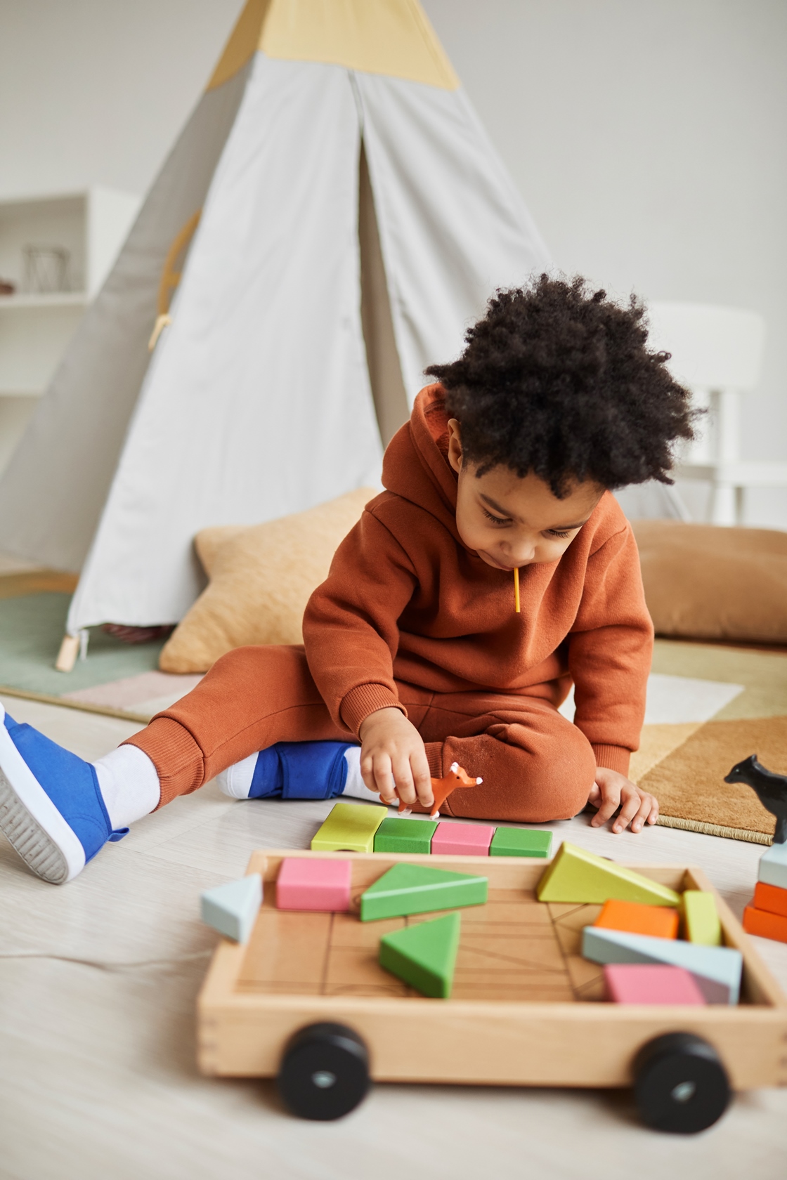 vertical-portrait-of-cute-african-american-toddler-playing-with-wooden-toys-in-cozy-kids-room